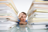 stressed man surrounded by stacks pf paper