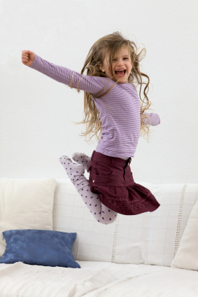 little girl jumping on bed
